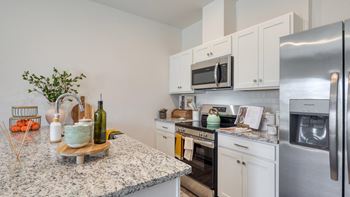 A kitchen with a granite countertop and stainless steel appliances.